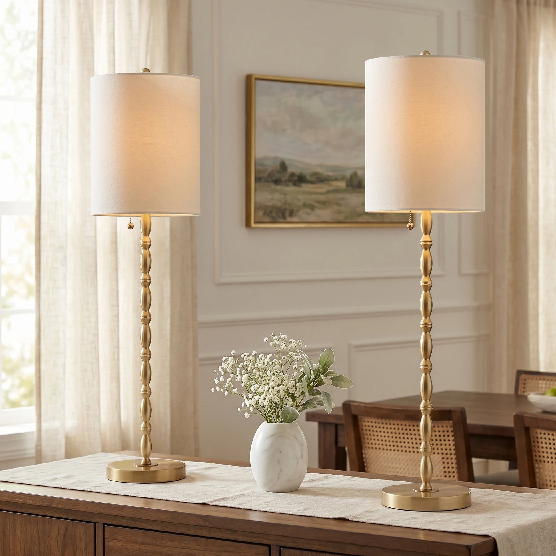 Set of two 28.5-inch tall modern brass-finished buffet lamps standing elegantly on a dining room sideboard.